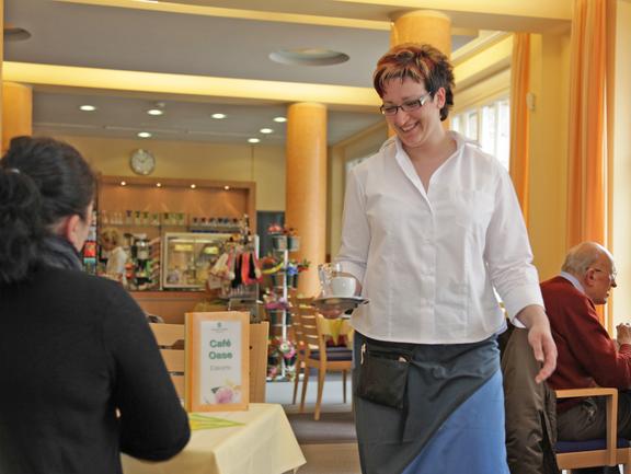 Freundliche Bedienung serviert einenGgast ein Heißgetränk